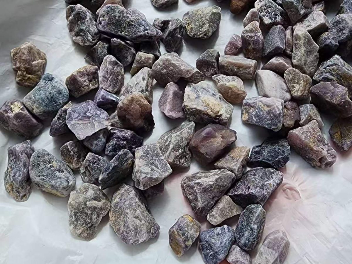 Purple and grey run-of-mine fluorspar lumps laid out on white paper
