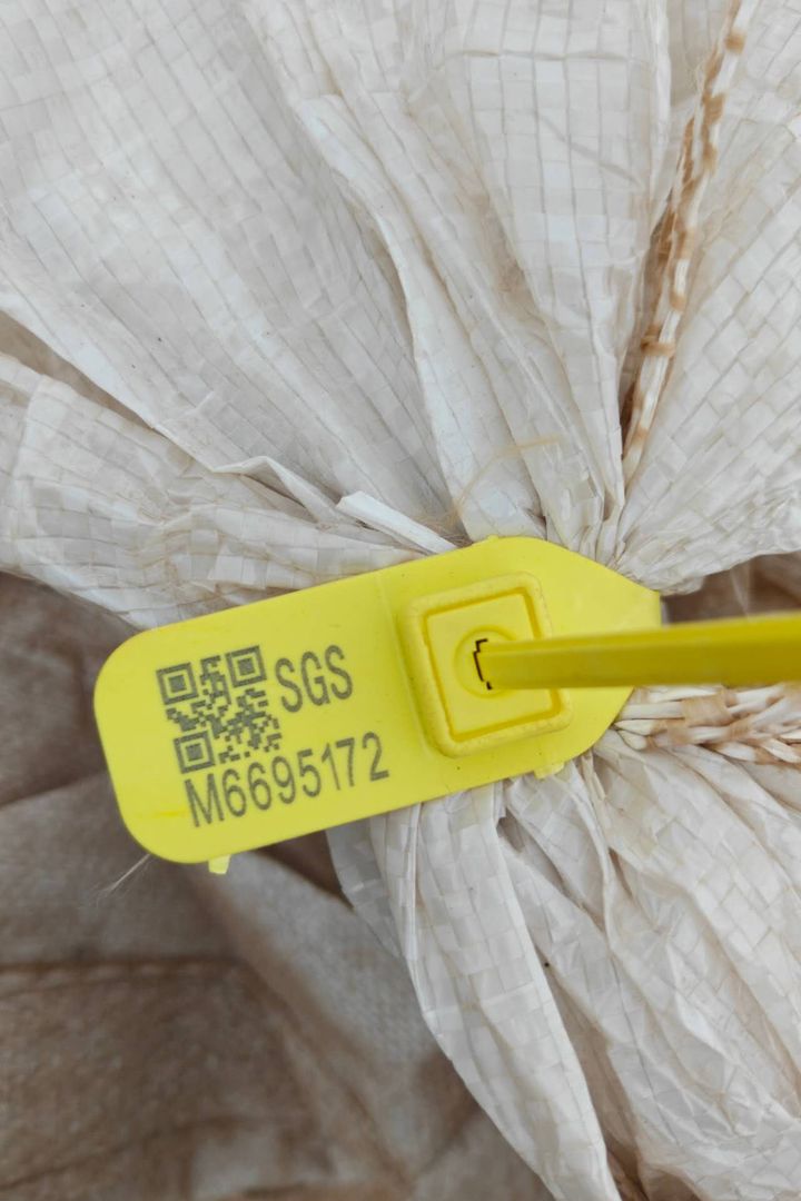 Yellow SGS numbered tamper seal fastened to the neck of a fluorspar sample bag